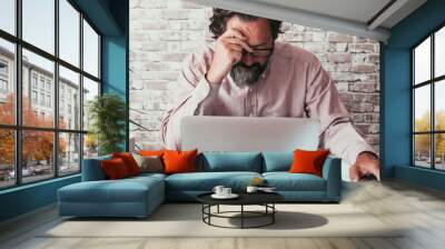 Portrait of man working on laptop with problems. Connections or security. Modern male adult people lifestyle. Professional freelance touching his front worries in front of a computer on the desk home Wall mural