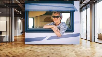 Portrait of young woman smiling at the camper van window. Happy tourist enjoy travel vanlife lifestyle. Renting rv caravan for vacation leisure. Caucasian female cheers and enjoy holiday destination Wall mural