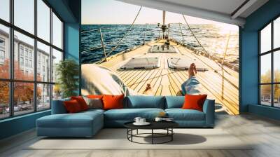 pov point of view of man legs laying and relaxing on the wooden sail boat deck alone with sunset in background - concept of travel people and freedom in summer holiday vacation Wall mural