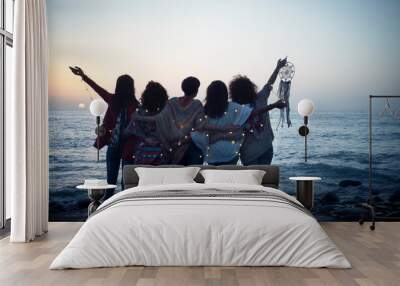 Romantic and dreamer concept image with five friends women hug each other viewed from back looking at the sunset holiding light - love freedom and wanderlust for group of people Wall mural