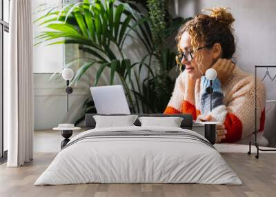 Serene young mature woman looking and reading on laptop online notification email. Pretty female people using computer at home relaxing sitting at the table alone. Modern indoor leisure activity web Wall mural