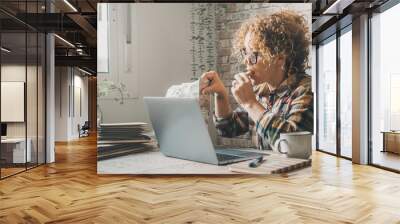 Side view of adult woman eating cookies sitting at the desk table in front of an open laptop and things to do. Busy entrepreneur new business lifestyle concept. Hungry female eat cookie while work Wall mural