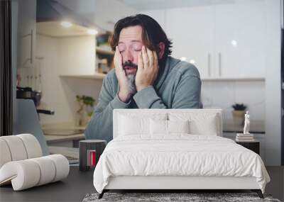 Tired man at home in morning wake up activity touching face and stretching after bad rest night. Coffee and computer online work concept. One person and insomnia health condition. Before job activity Wall mural