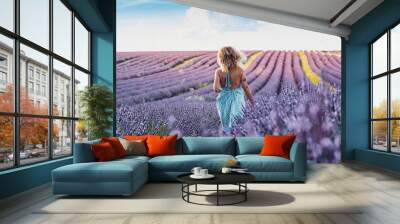 Travel wanderlust lifestyle people concept. Back view portrait of woman walking in lavender field wearing blue trendy boho dress. Blue sky in background. Concept of vacation in scenic destination. Wall mural