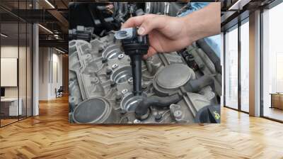 Close up of hand inserting new ignition coil into engine  Wall mural