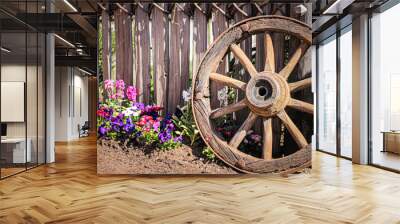 old wooden wagon wheel in a garden and a fence Wall mural