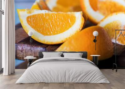 Orange wedges on a kitchen cutting board on blue background Wall mural