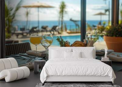 123. Oceanfront restaurant dining setup with a clear view of the pool and ocean, showcasing a variety of dishes, drinks, and a basket of fresh bread with butter, creating a perfect seaside meal Wall mural