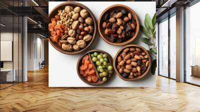 62. High-angle view of a mix of dried fruits and nuts on wooden plates, with a branch of young green leaves, isolated on a white background, symbolizing the Jewish holiday Tu Bishvat Wall mural