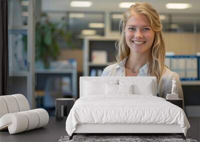 78. Professional office interior with a smiling blond young woman holding a blue documents folder, capturing a moment of confidence and happiness Wall mural