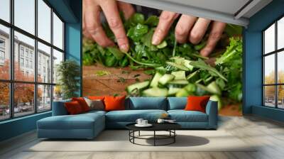 87. Close-up of hands preparing a healthy salad in a kitchen, with various green vegetables neatly arranged on a cutting board Wall mural