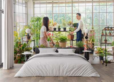 Portrait gardener young asian man woman two person standing smiling looking hand holding help decorate tree leaf green in calm work in room shop home plant white wall. hobby job happy and care concept Wall mural