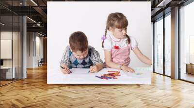 Little boy and girl draw with crayons sitting at table Wall mural