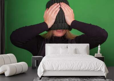 Young woman covers her face with a knitted hat Wall mural