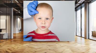 An allergist or dermatologist examines red spots on a child’s face. The boy suffers from a rash, hives and itching. Food Allergy, Insect Bite, Measles or Chicken Pox Wall mural