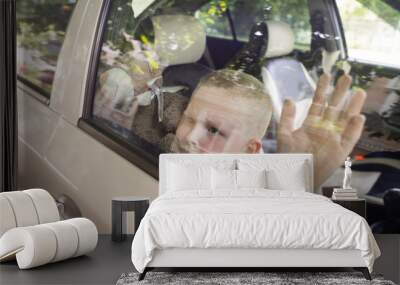 Child locked in car. Blond boy is closed in auto without water. He is hot and his face is red. Irresponsible parents left the child alone in a hot car. Concept of poor care for kids. Wall mural