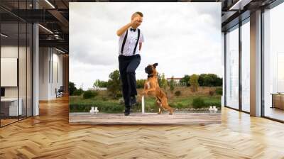 Creative hipster wedding by the sea. The bride is in a pink dress and veil, the groom is in beautiful trousers with suspenders and a youth shirt. The dog is present at the wedding instead of a witness Wall mural