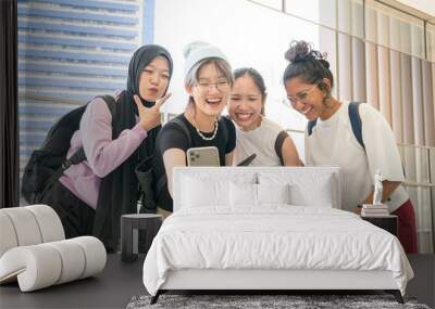 Group of young happy Asian women with diverse ethnicity laughing having fun while taking selfie with a smartphone. Wall mural