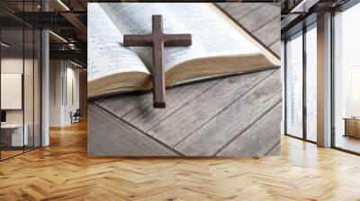 Wooden cross on top of an open bible and wood table. Copy space. Wall mural