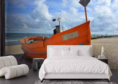 Orange colored traditional fishing boat at the baltic sea coast in Poland Wall mural