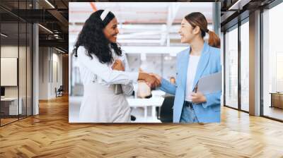 Business women, handshake and welcome, introduction and hello to new intern while walking in office. Happy, excited and diversity workers shaking hands for support, teamwork or onboarding partnership Wall mural