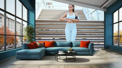 Fitness, smartwatch and health tracking with sports woman checking pulse and progress during exercise on building steps in a city. Training, time and cardio workout by Mexican girl monitor wellness Wall mural