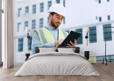 Male engineer checking data on digital tablet and inspecting construction site. Technician in a hardhat doing management and project planning outdoors. Skilled worker looking or overseeing operations Wall mural