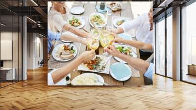 Cheers to good food and the people were sharing it with. Shot of a family sharing a toast while enjoying a meal together. Wall mural