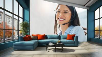 Leave the hard work to me. Shot of an attractive young saleswoman sitting alone in the office and wearing a headset. Wall mural