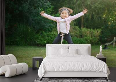 Shes just a burst of energy. Portrait of an adorable little girl jumping outdoors. Wall mural