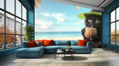 Adorable black cat wearing a witch hat and drinking from a coconut on a sunny tropical beach during Halloween Wall mural