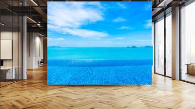 Beautiful luxury outdoor infinity swimming pool with tropical sea ocean and white cloud blue sky background Wall mural