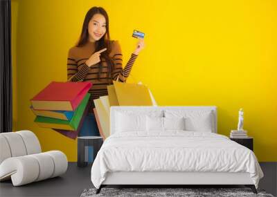 Portrait beautiful young asian woman use credit card for shopping with colorful shopping bag on yellow background Wall mural