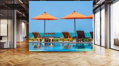 Umbrella and chair around outdoor swimming pool neary sea in hotel resort Wall mural