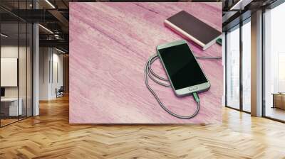 Smartphone charging with power bank on wood background,filter effect Wall mural