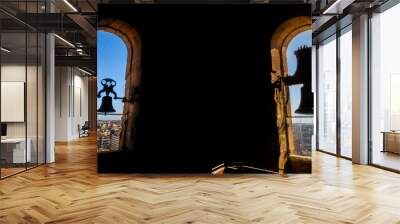 Silhouettes backlit by the evening sun of two restored bronze bells of the Torre de la Clerecia with views of the city of Salamanca from above. Wall mural