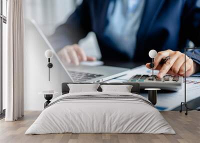 Close up view of Businesswomen or Accountants using calculator and a laptop computer to analyze business report graphs and finance charts at the workplace, financial and investment concept. Wall mural