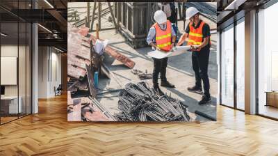 Engineer in hardhat and orange jacket posing on building site. civil engineer or architect with hardhat on construction site checking schedule on plan. Wall mural