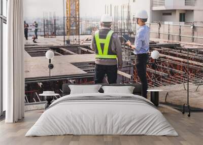 Two engineer in hardhat and orange jacket posing on building site. civil engineer or architect with hardhat on construction site checking schedule on plan. Two business man construction site engineer. Wall mural