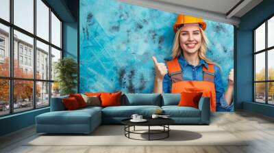 A beautiful blonde-haired fair-skinned woman wearing a hard hat and a construction worker's uniform smiles happily and optimistically, giving a thumbs-up to show good work and approval. Wall mural