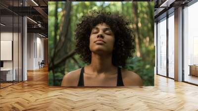 Woman with closed eyes meditating in the forest surrounded by trees Wall mural