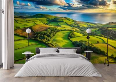 Breathtaking aerial view of idyllic countryside scenery featuring undulating hills, vibrant green fields, and scattered woodland, merging with the distant horizon and serene ocean. Wall mural