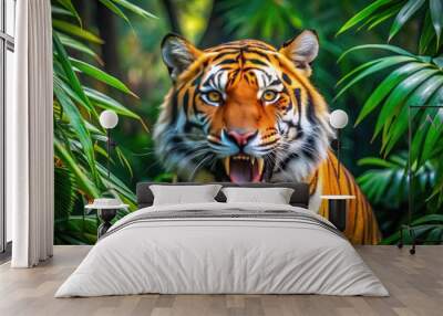 Majestic orange and black tiger unleashes a deafening roar, baring sharp teeth and claws, amidst a lush green jungle backdrop with vibrant foliage surrounding. Wall mural