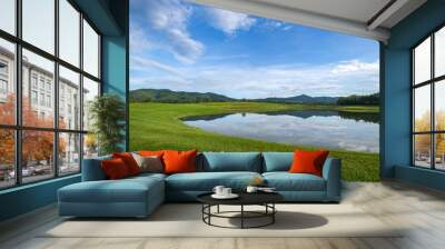 Scenic View Of Grassy Field near lake with cloudy sky Wall mural