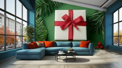 A beautifully wrapped Christmas gift with a red ribbon, surrounded by festive greenery and holiday decorations. Wall mural