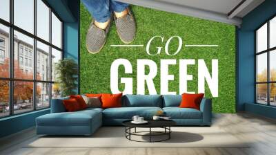 Go green banner with girl standing on green grass background, ecological concept Wall mural