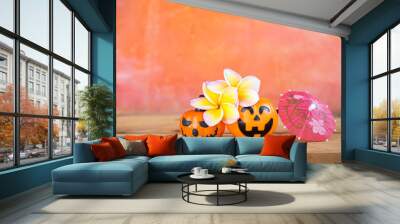 Halloween pumpkin with Plumeria flower and pink paper umbrella over blurred background, Happy Halloween card background idea Wall mural