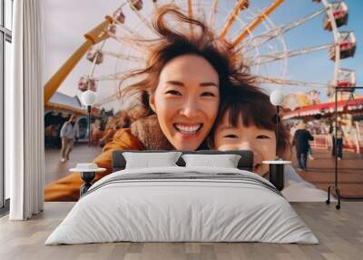 Beautiful young Asian mother taking a selfie with her cute daughter on a ferris wheel Wall mural