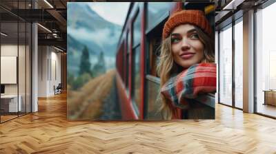 Inspiring female traveler and travel blogger looks out the window of a tourist train in beautiful mountains. Wall mural