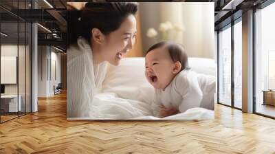 New Asian mom playing with cute newborn baby on bed smiling and happy and baby Wall mural